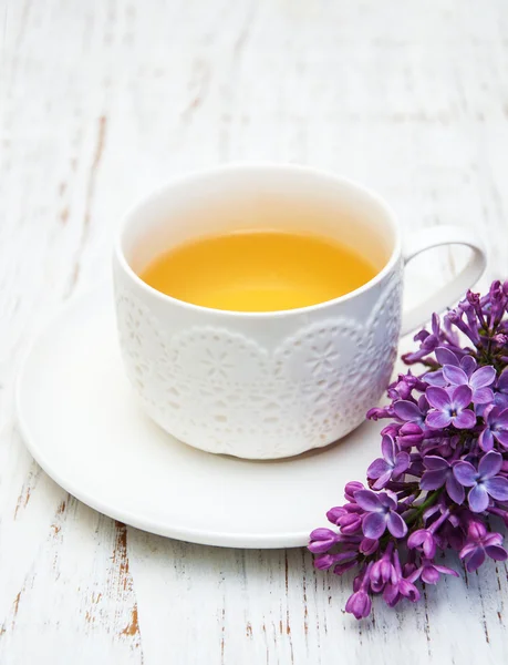 Kopje thee en lila bloemen — Stockfoto