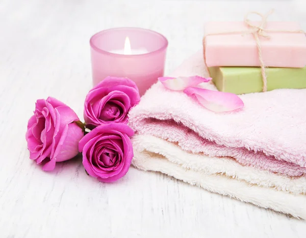 Badhanddoeken, kaars en zeep met roze rozen — Stockfoto