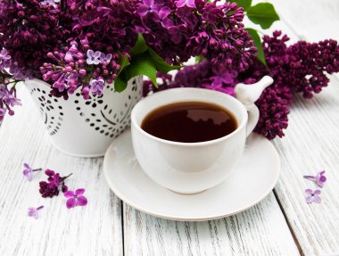 Fincan çay ve eflatun çiçekler