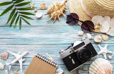 Yaz yolculuğu konsepti. Eski film kamerası, şapka, kabuk ve palmiye yaprakları mavi ahşap arka planda.