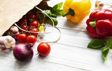 Sağlıklı yemek geçmişi. Kese kağıdında sağlıklı yiyecekler, beyaz ahşap arka planda sebzeler.