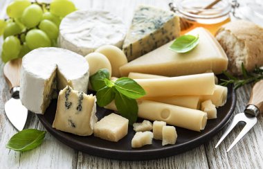 Beyaz ahşap arka planda çeşitli peynir çeşitleri