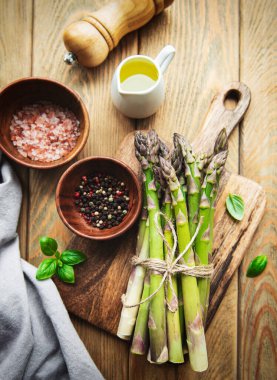 Köy ahşap bir masada taze yeşil kuşkonmaz demeti.