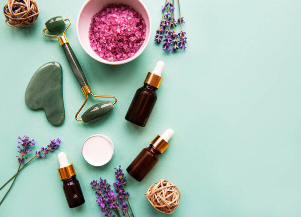 Natural organic SPA cosmetic with lavender. Flat lay bath salt, spa products and lavender flowers on green background. Skin care, beauty treatment concept
