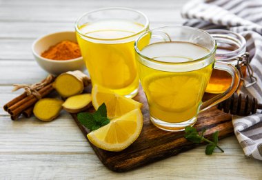Beyaz ahşap arka planda zerdeçal, zencefil, limon ve bal içeren enerji toniği