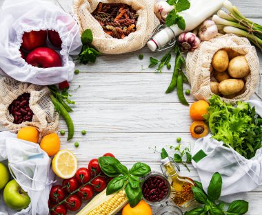 Sıfır atık alışverişi ve sürdürülebilir yaşam tarzı konsepti, çeşitli çiftlik organik sebzeleri, tahıllar, makarna ve meyveler yeniden kullanılabilir paketleme süpermarketlerinde. Boşluk üst görünümünü, tahta arkaplanı kopyala