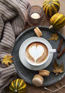 Güzel ve romantik sonbahar kompozisyonu bir fincan kahve, sıcak battaniye, dekoratif çizgili balkabakları, mumlar ve sonbahar yaprakları. Sıcak bir sabah. Hygge ev içi..