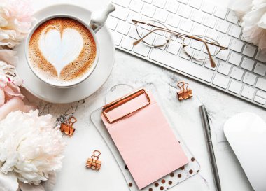 Düz manzaralı kadınlar bürosu masasında çiçeklerle yatıyordu. Dizüstü bilgisayarlı, çiçekli şakayıklı, aksesuarlı, defterli, gözlüklü, beyaz arka planda bir fincan kahveli bir kadın çalışma alanı. Tatil arkaplanı. Boşluğu kopyala