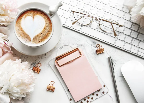 Düz manzaralı kadınlar bürosu masasında çiçeklerle yatıyordu. Dizüstü bilgisayarlı, çiçekli şakayıklı, aksesuarlı, defterli, gözlüklü, beyaz arka planda bir fincan kahveli bir kadın çalışma alanı. Tatil arkaplanı. Boşluğu kopyala