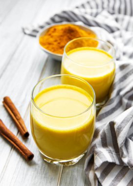 Sarı zerdeçal latte. Beyaz mermer zemin üzerinde tarçın, zerdeçal, zencefil ve bal içeren altın süt.