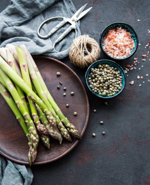 Bir sürü çiğ kuşkonmaz siyah beton arka planda farklı baharat ve malzemelerle yapılır. Üst manzara, düz uzanma.
