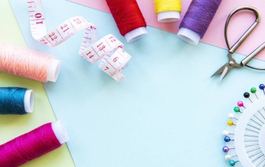 Mavi pastel arka planda aksesuarlar dikiyorum. Dikiş iplikleri, iğneler, iğneler ve dikiş santimetresi. Üst manzara, düz uzanma.
