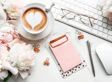 Düz manzaralı kadınlar bürosu masasında çiçeklerle yatıyordu. Dizüstü bilgisayarlı, çiçekli şakayıklı, aksesuarlı, defterli, gözlüklü, beyaz arka planda bir fincan kahveli bir kadın çalışma alanı. Tatil arkaplanı. Boşluğu kopyala