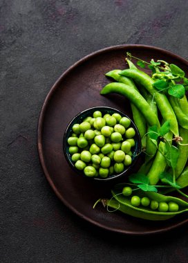 Siyah beton zemin üzerinde taze kabuklu yeşil bezelyeler, üst ya da düz yatıyordu