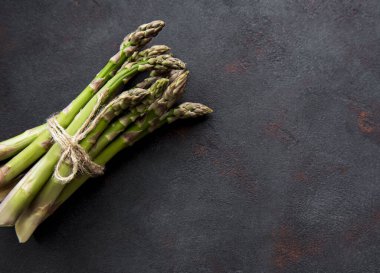 Siyah beton arka planda taze yeşil kuşkonmaz. Düz yatıyordu