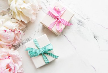 Beyaz arka planda şölen kompozisyonu: şakayık çiçekleri, hediye kutuları. Üst görünüm, alanı kopyala.