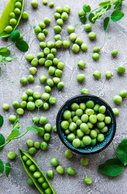 Gri bir zeminde yeşil bezelyeler. Yukarıdan görüntüle.
