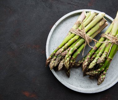 Siyah beton arka planda taze yeşil kuşkonmaz. Düz yatıyordu