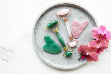 Güzellik masajı için yeşim yüz silindirleri. Düz beyaz mermer zemin üzerinde yatıyordu