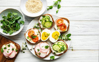 Sağlıklı sebzeli sandviçler ve ahşap bir masada mikro yeşiller.
