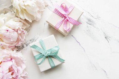 Beyaz arka planda şölen kompozisyonu: şakayık çiçekleri, hediye kutuları. Üst görünüm, alanı kopyala.