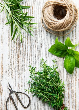 Ahşap arka planda taze bitkiler ve sicim.