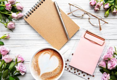 Çalışma alanı, günlük, defter, pano, beyaz arka planda güller. Merkez ofis masası. Üst görünüm kadınsı arka plan. Düz yatış, üst görünüm