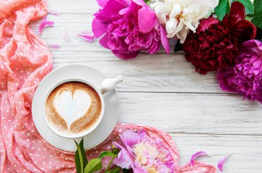 Beyaz ahşap arka planda pembe şakayık ve bir fincan kahve. Çiçek arkaplan. Üst görünüm.