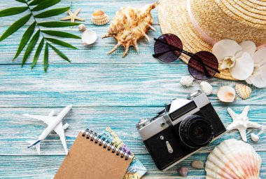 Yaz yolculuğu konsepti. Eski film kamerası, şapka, kabuk ve palmiye yaprakları mavi ahşap arka planda.
