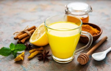 Sarı zerdeçal latte. Beton zemin üzerinde tarçın, zerdeçal, zencefil ve bal içeren altın süt.