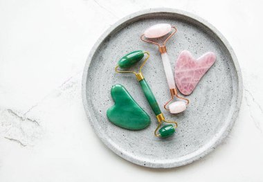 Güzellik masajı için yeşim yüz silindirleri. Düz beyaz mermer zemin üzerinde yatıyordu