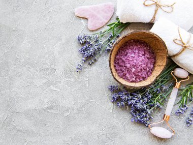 Lavantalı doğal organik SPA kozmetik seti. Düz banyo tuzu ve yüz silindiri, beton arka planda. Cilt bakımı, güzellik tedavi konsepti