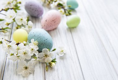 Ahşap arka planda bahar çiçekleri olan renkli Paskalya yumurtaları. Renkli Yumurta Tatil Kenarı.