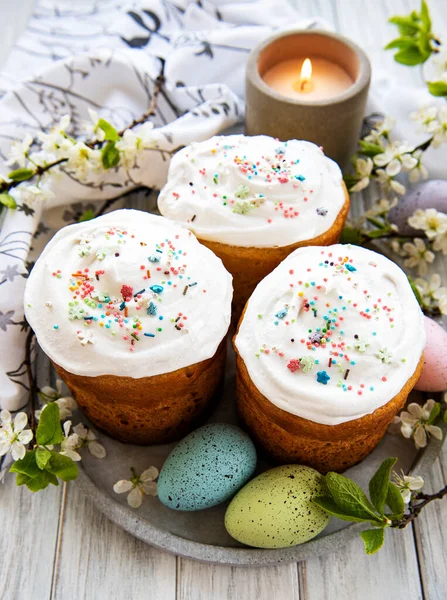 Traditional Easter sweet bread decorated with sugar glaze. Easter orthodox cake and cherry blossom twig in the background