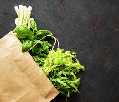 Siyah arka planda kağıt torbada taze yeşiller.