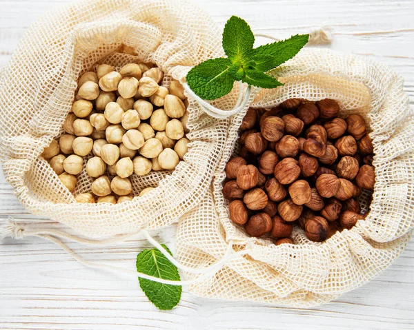 Geschilde Hazelnoten Een Katoenen Zak Witte Houten Ondergrond — Stockfoto