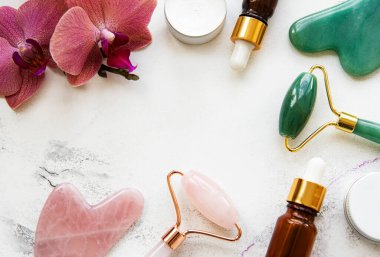 Beyaz mermer arka planda kozmetik ürünü ile yüz masajı yeşim silindiri