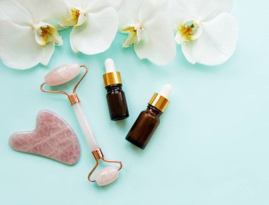 Pastel yeşil arka planda kozmetik ürünü olan yüz masajı yeşim silindiri.