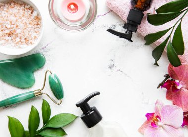 Beyaz mermer arka planda kozmetik ürünü ile yüz masajı yeşim silindiri