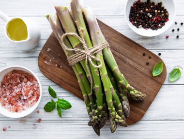 Bir sürü çiğ kuşkonmaz, ahşap zemin üzerinde farklı baharat ve malzemeler barındırır. Üst manzara, düz uzanma.