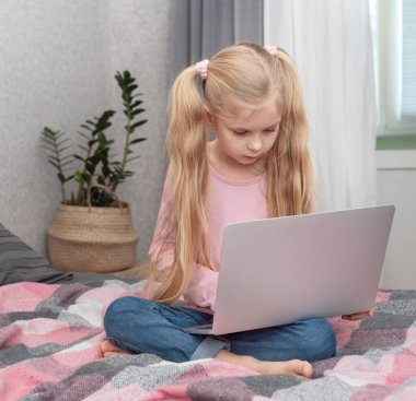 Sarışın kız evde internette dizüstü bilgisayarla ders çalışıyor.