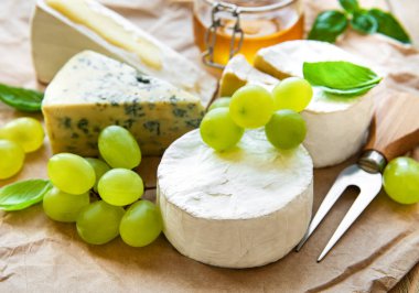 Masada çeşitli peynir, fesleğen ve üzümler var.