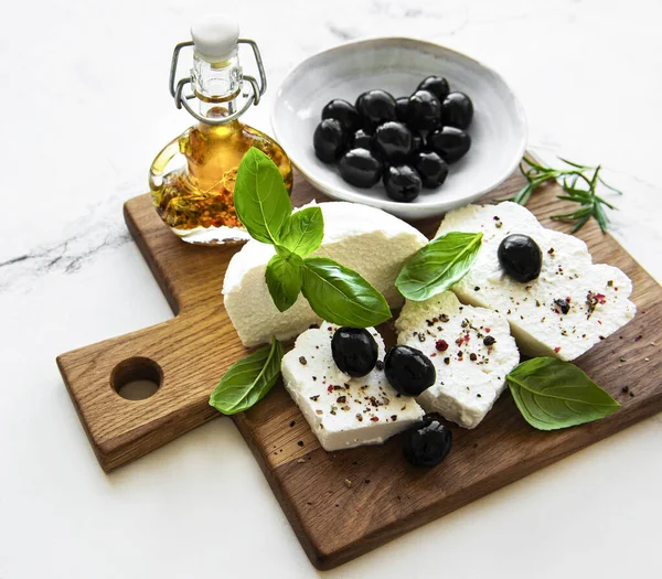 A fresh ricotta with basil leaves and olives  on wooden board, italian food concept