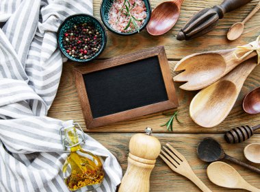 Boş tebeşir tahtası ve beyaz ahşap arka planda baharatlı mutfak aletleri.