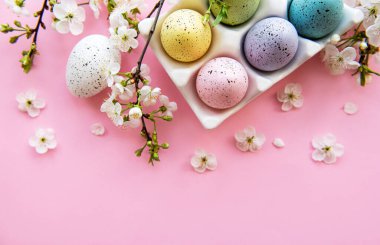 Pembe yüzeyde boyanmış Paskalya yumurtaları ve yumurta tepsisinin üst görüntüsü