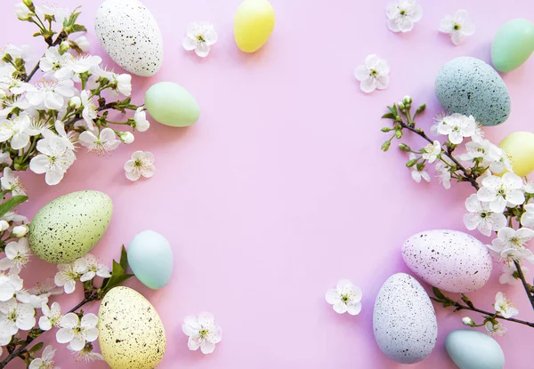 Pembe arka planda bahar çiçekleri olan renkli Paskalya yumurtaları. Renkli Yumurta Tatil Kenarı.