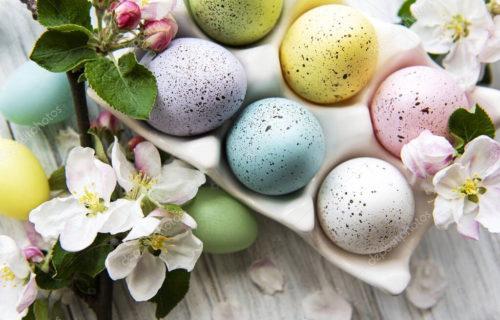 Top view of  painted easter eggs and egg tray on white wooden surface