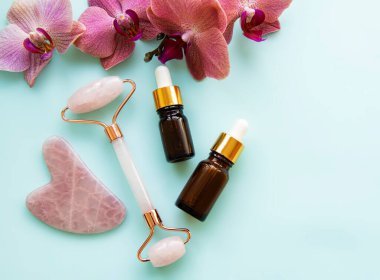 Pastel yeşil arka planda kozmetik ürünü olan yüz masajı yeşim silindiri.