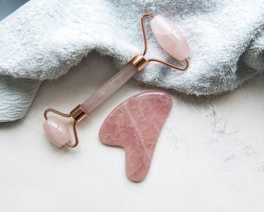 Güzellik masajı terapisi için yeşim yüz silindiri. Mavi havlu arka planında düz uzandı