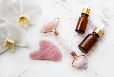 Beyaz mermer arka planda kozmetik ürünü ile yüz masajı yeşim silindiri